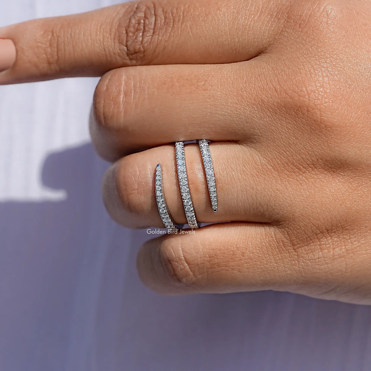 Silver moissanite spiral eternity band with round-cut stones, close-up on hand