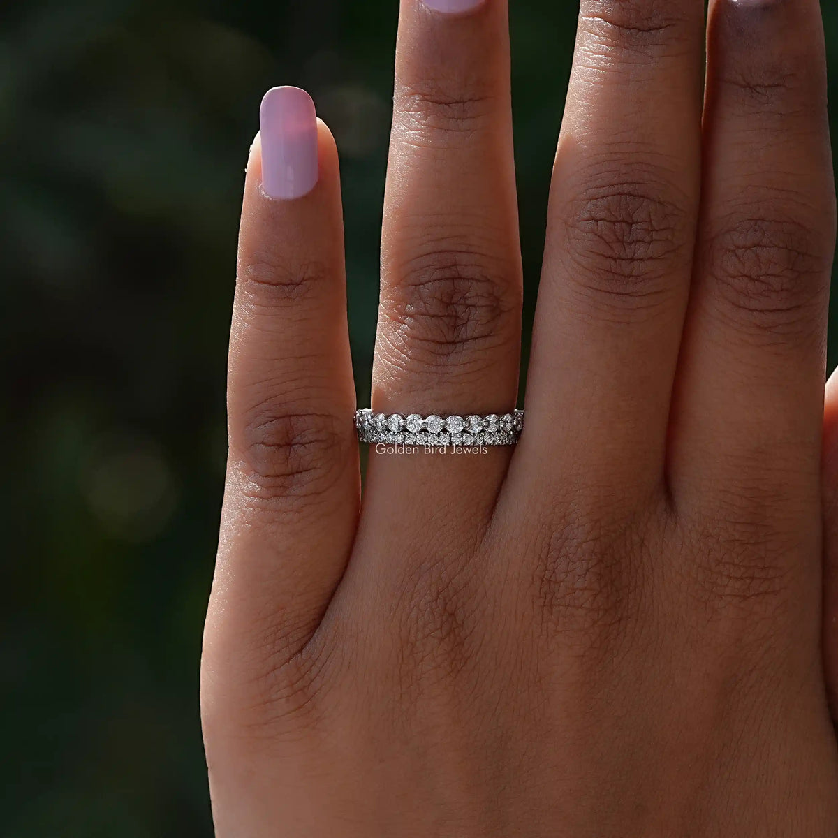 Silver two-row eternity band ring with round stones on a relaxed hand