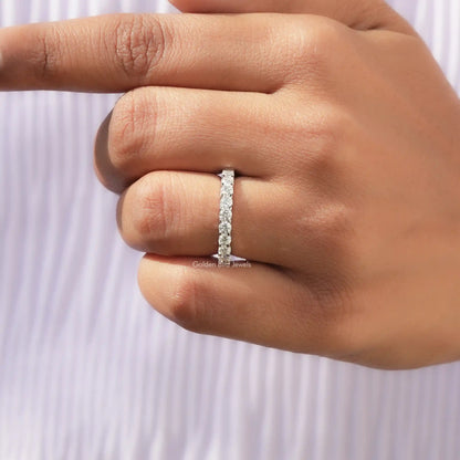 Round moissanite full eternity wedding band on finger, slim profile with bright round stones