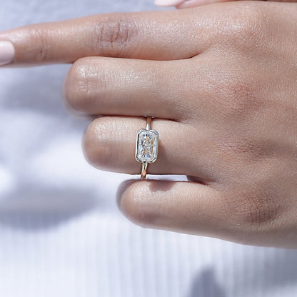 Radiant-cut moissanite solitaire ring on finger with half bezel and thin band