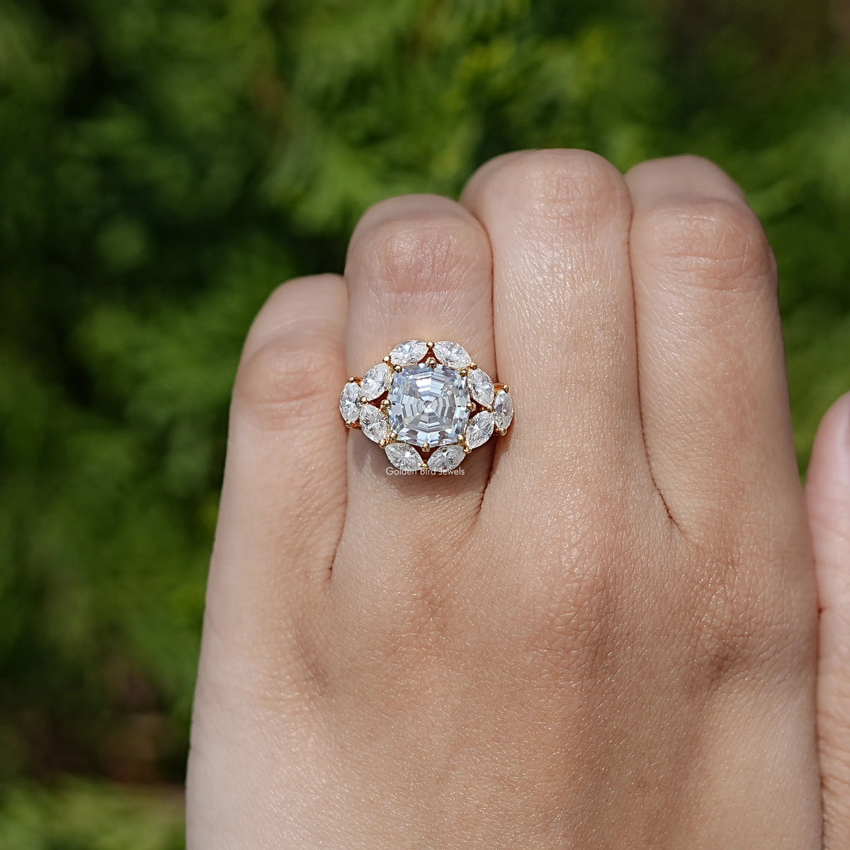Step-cut moissanite halo ring with round side stones and detailed setting on palm