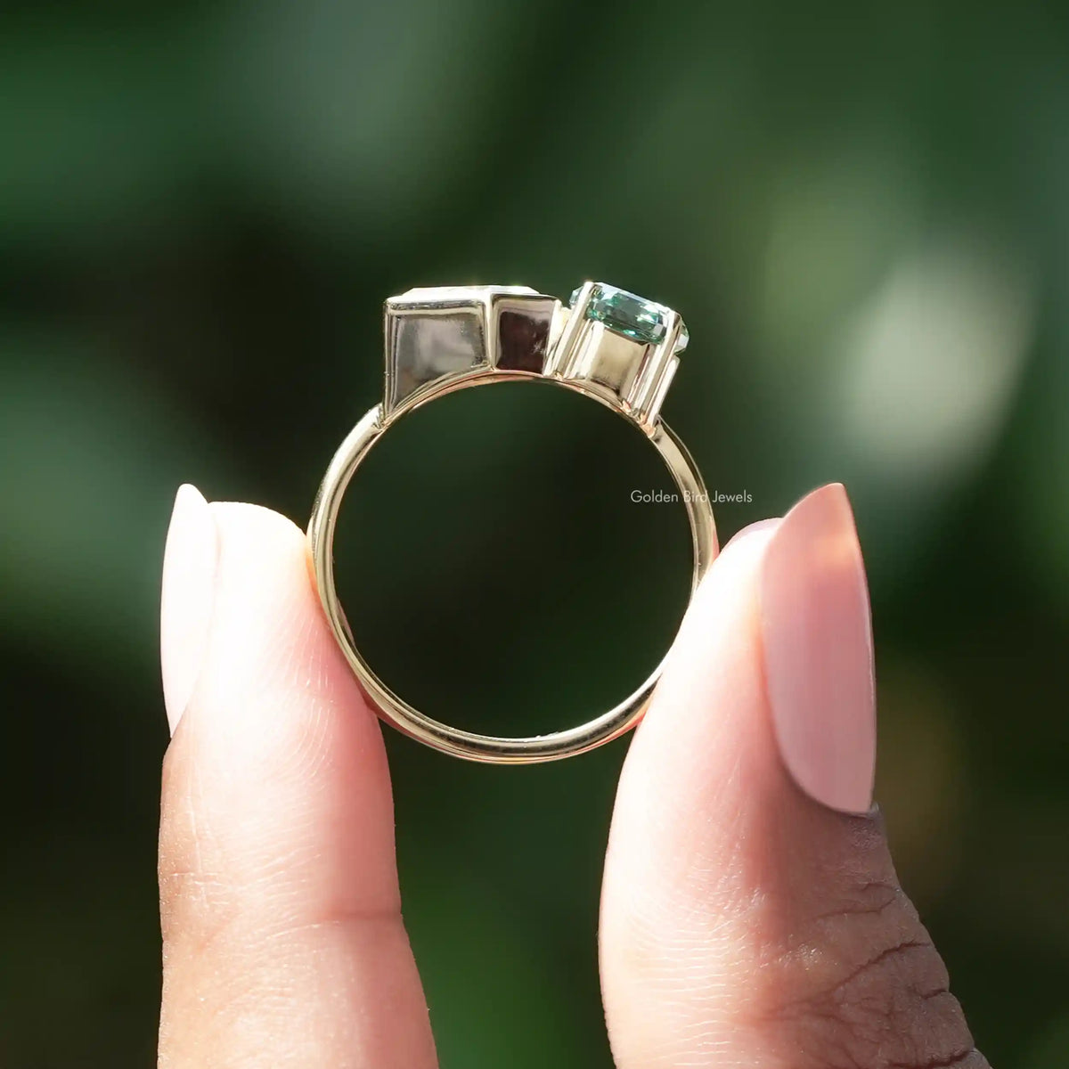 Toi et moi engagement ring viewed from front with green center and clear side stones