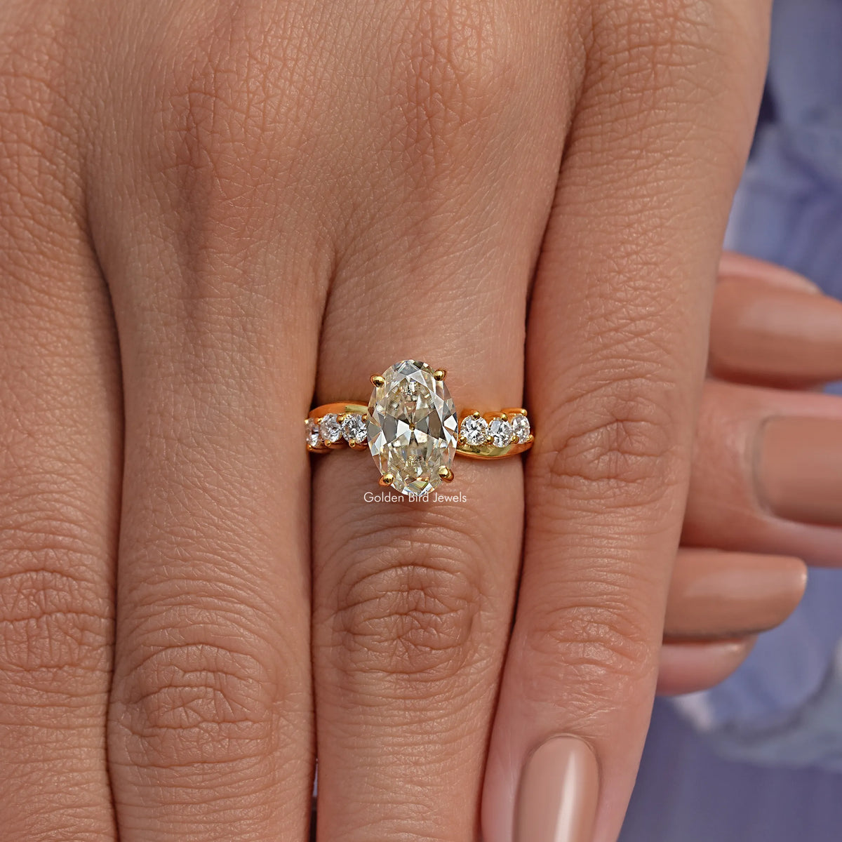 Gold-tone infinity ring on hand with oval old mine center stone and round accent stones
