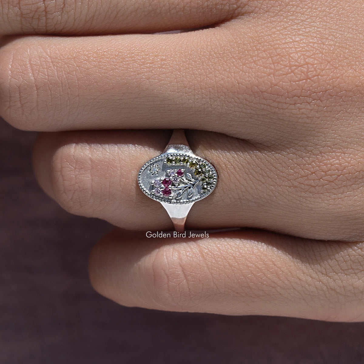 Silver-tone oval floral signet ring with purple-pink gemstones and decorative border