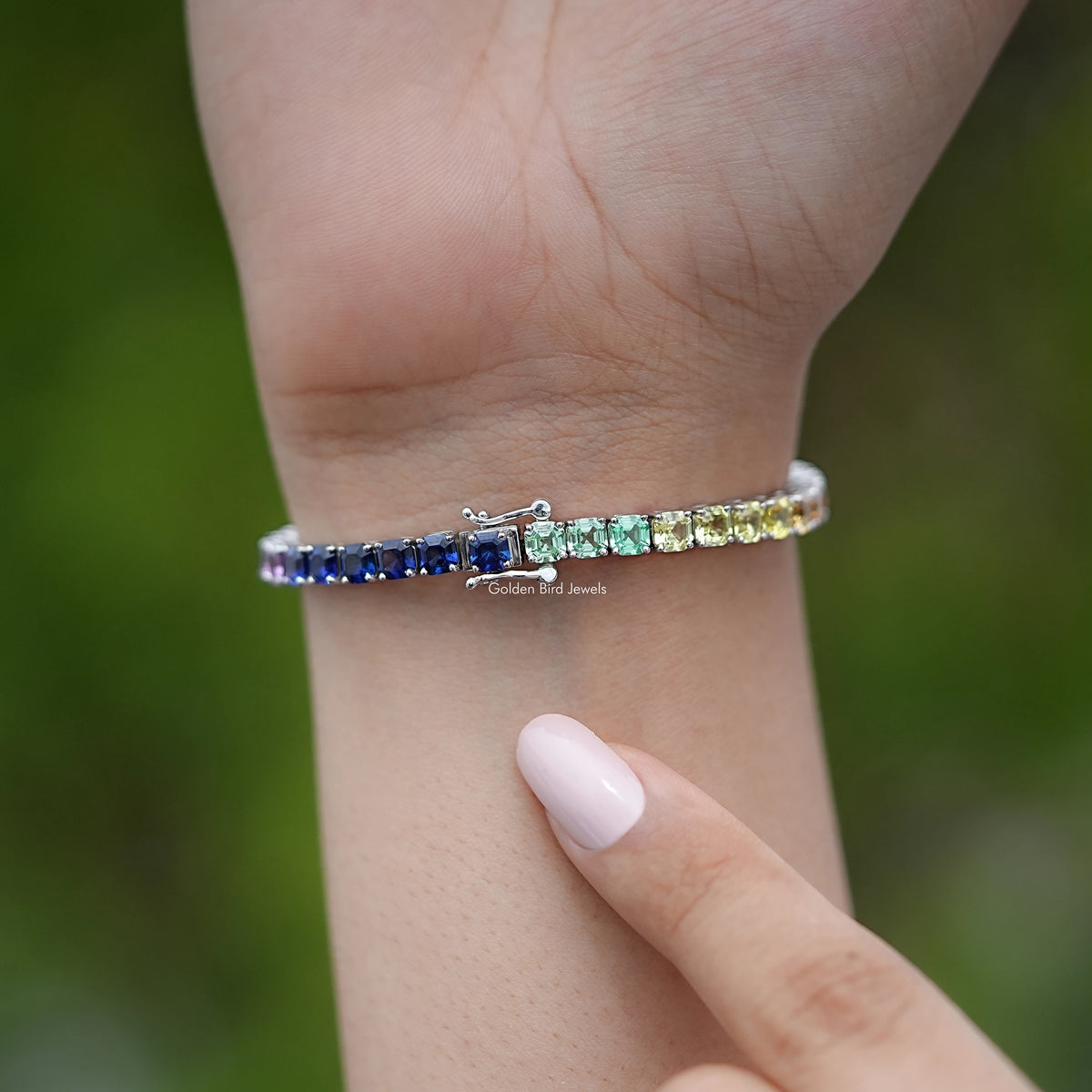 Gem tennis bracelet on wrist, blue and purple stones in a silver prong row.