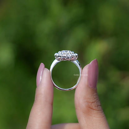 Silver round halo engagement ring held between fingers