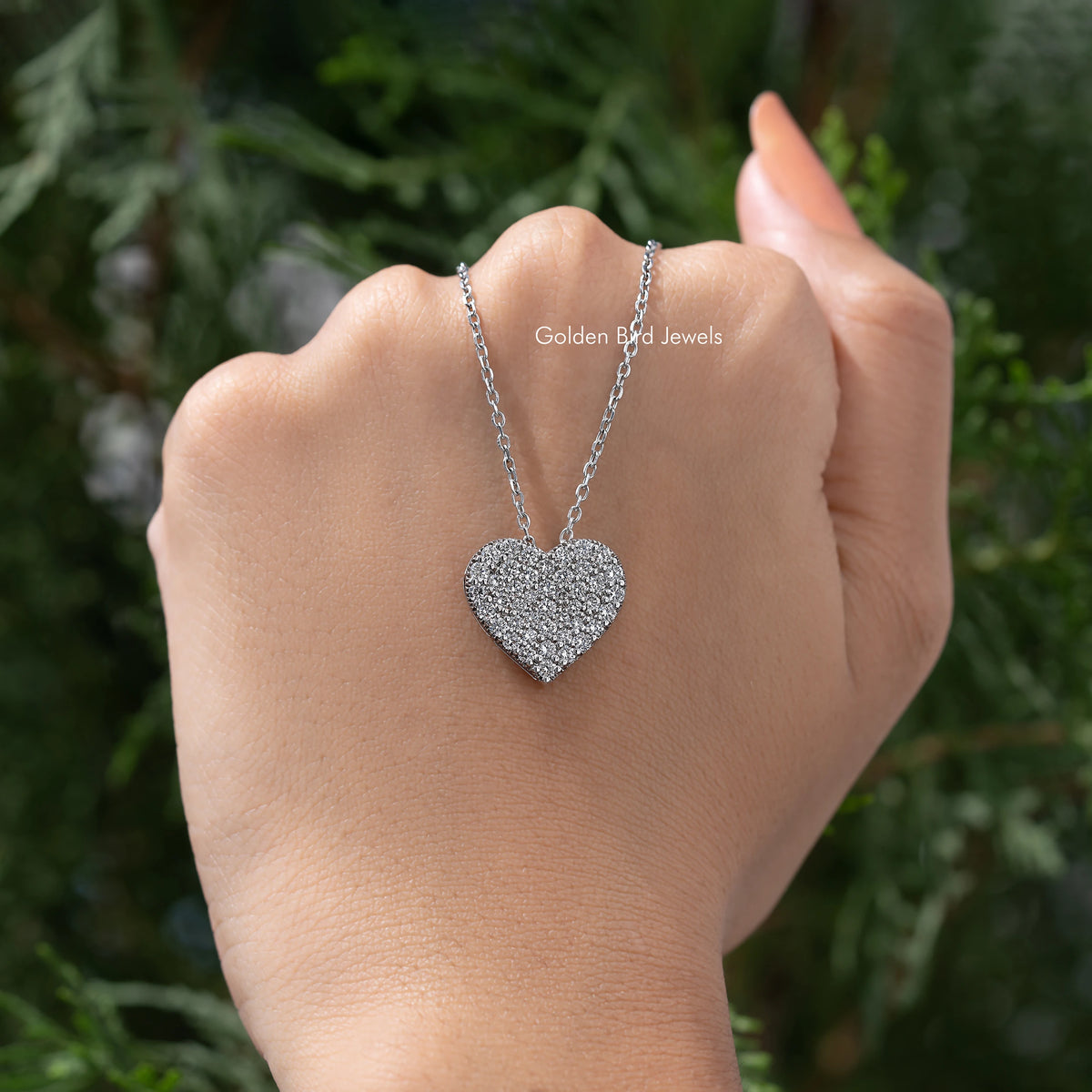 Silver-tone heart pendant on necklace resting on open palm