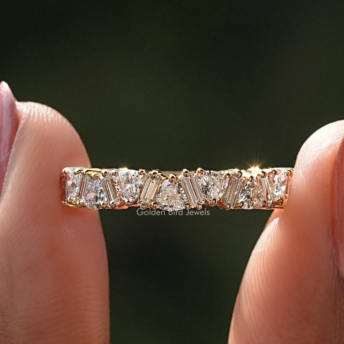 Trillion and Baguette Diamond Eternity Wedding Band Held Between Fingers