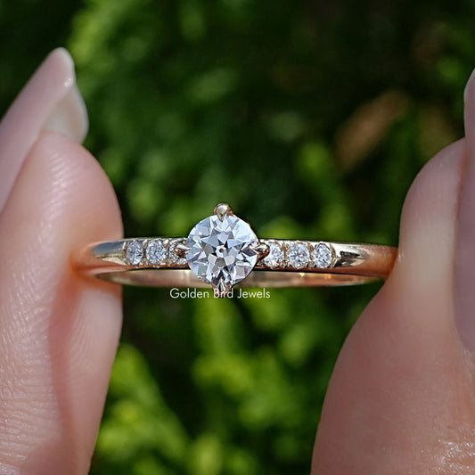 Old European Round Cut Lab Diamond Accent Ring Held Between Fingers