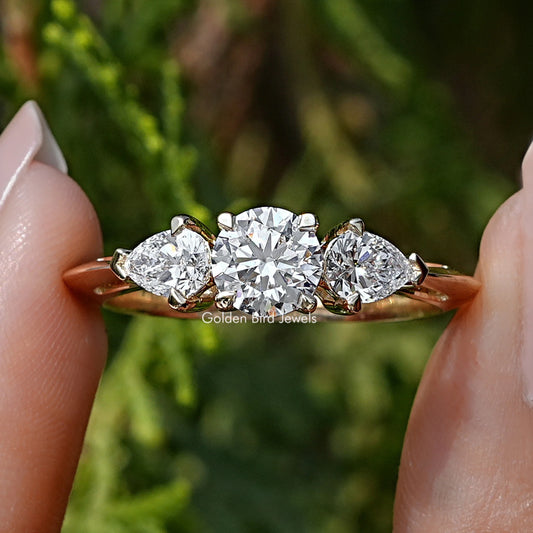 Pear and Round Cut Lab Diamond Three Stone Ring Held Between Fingers