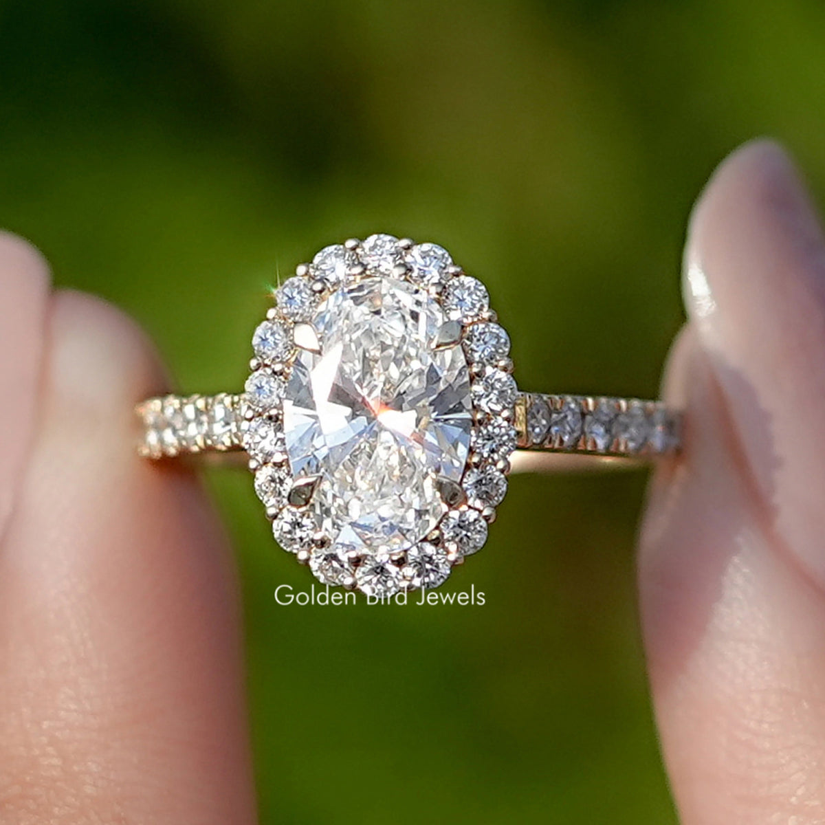 Oval Cut Lab Diamond Halo Engagement Ring Held Between Fingers