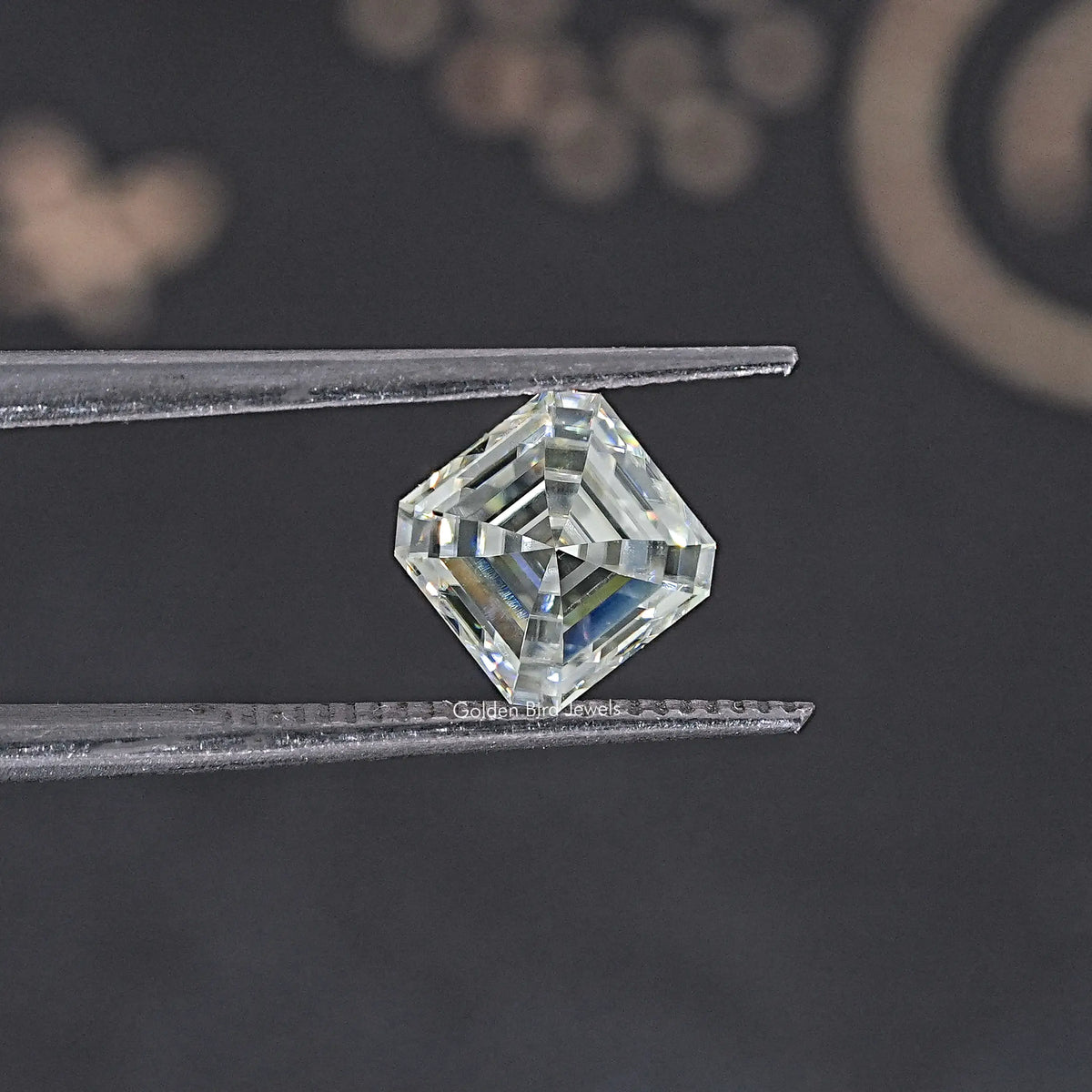 Asscher-cut moissanite loose stone in tweezers, clear off-white step-cut facets