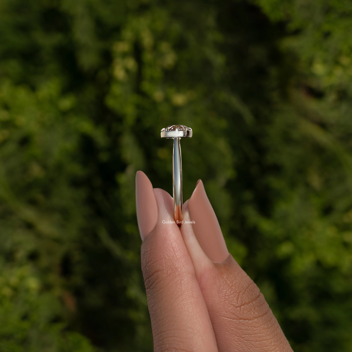 Side view of round moissanite ring showing prongs and slim gold-tone band