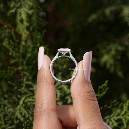 Sterling silver round moissanite bezel wedding ring, ring profile held between fingers