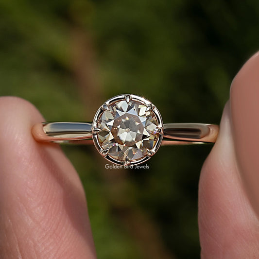 Close-up of round moissanite ring with prong-set center stone and gold-tone band
