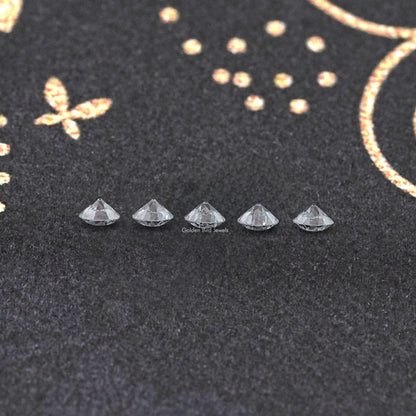 Set of five round lab-grown diamonds in prong settings on dark pad