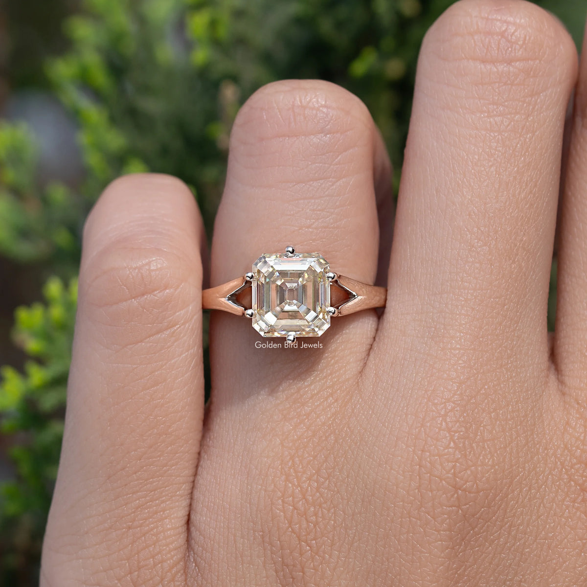 Yellow asscher-cut moissanite ring on finger, split shank with square four-prong setting