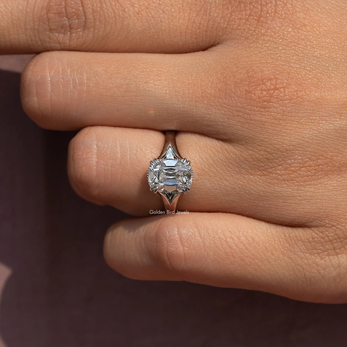 Cushion-cut diamond split-shank ring with halo, worn on finger