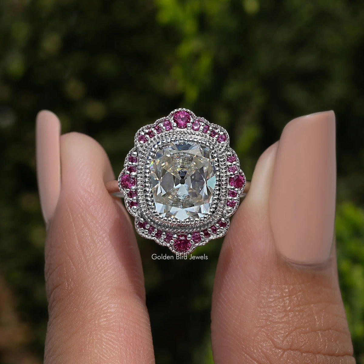 Sterling silver halo ring with cushion-cut moissanite center and pink stone border
