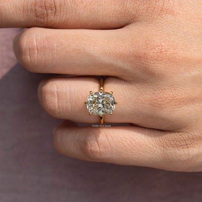 Gold-tone cushion solitaire engagement ring with square center stone, close-up on hand