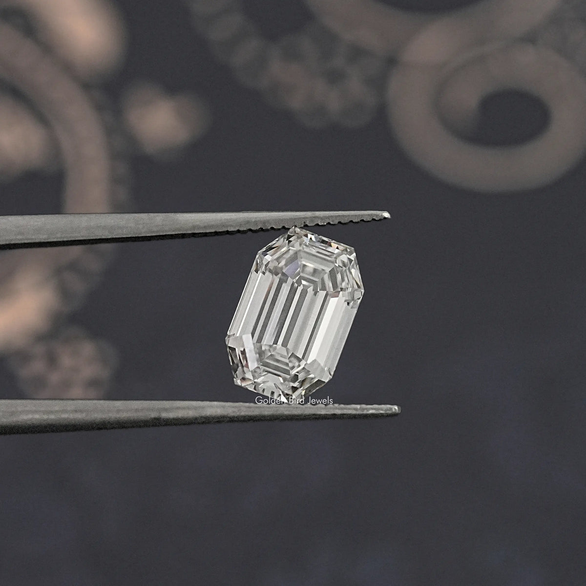 Emerald-cut lab-grown diamond held between metal tweezers, angled close-up