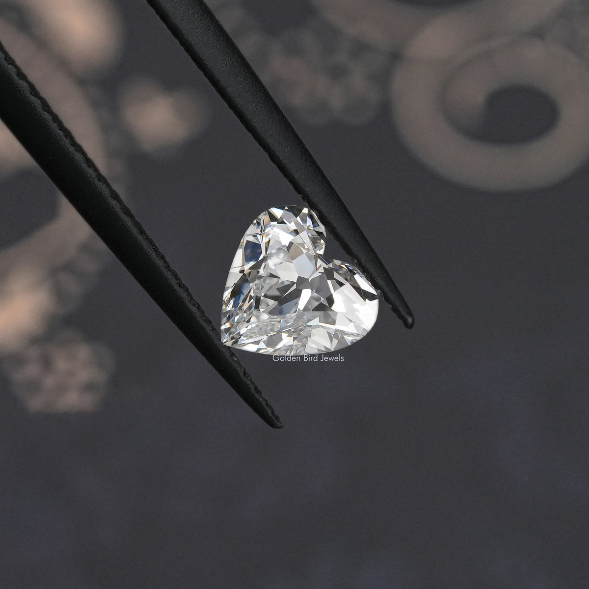 Heart-cut loose diamond in black tweezers, close-up on its facets