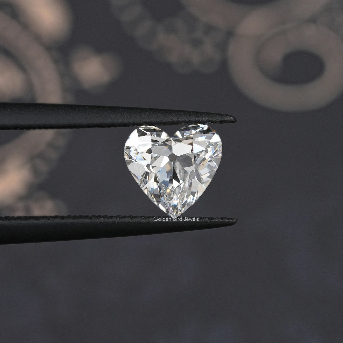 Heart-cut loose diamond held in black tweezers, bright faceted sparkle