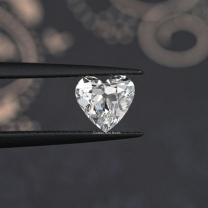 Heart-cut loose diamond held in black tweezers, bright faceted sparkle