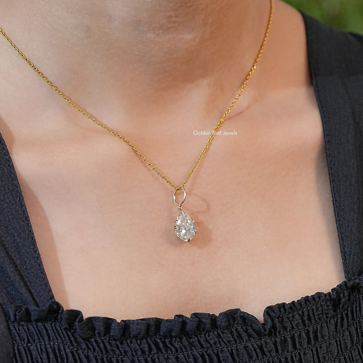 Gold-tone pear-cut pendant showing teardrop moissanite stone in bezel setting