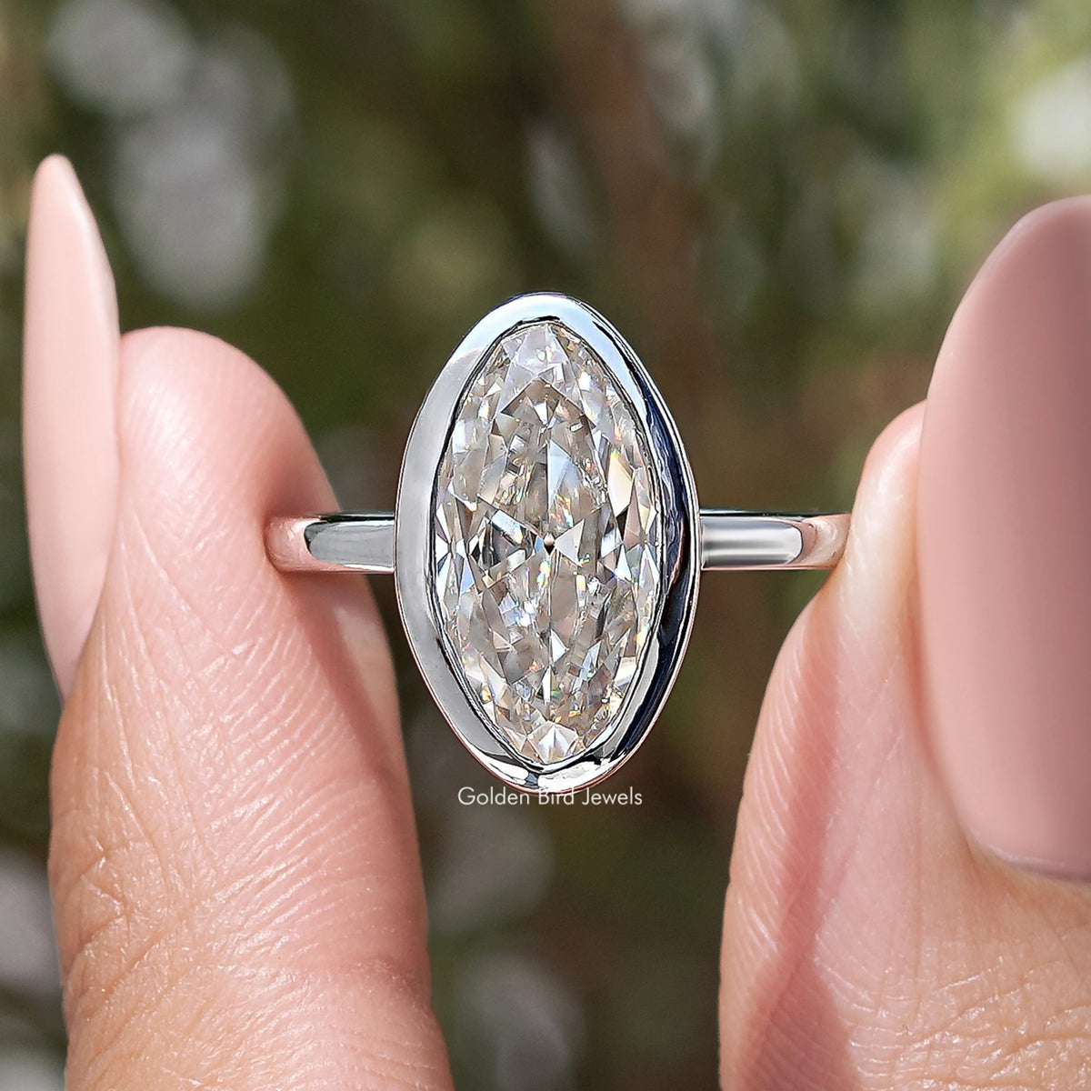 Front close-up of oval bezel-set moissanite solitaire ring, silver-toned band