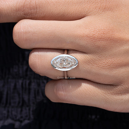 Side view of oval bezel-set moissanite solitaire ring, silver-toned band and setting