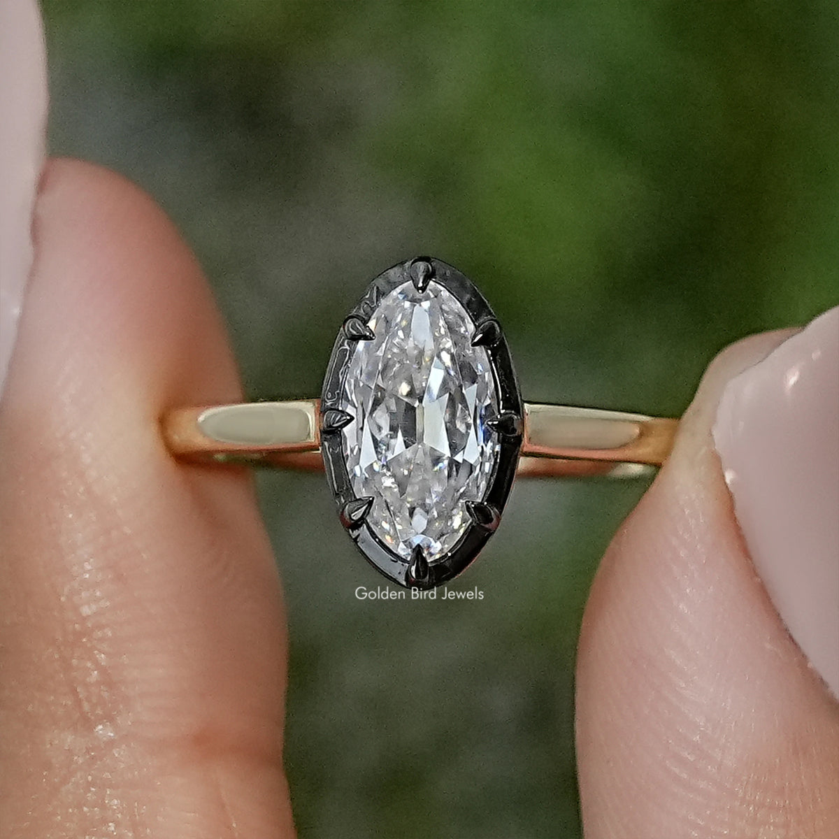 Oval moissanite bezel-set solitaire ring on gold-tone band, close-up side view