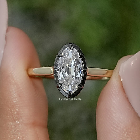 Oval moissanite bezel-set solitaire ring on gold-tone band, close-up side view