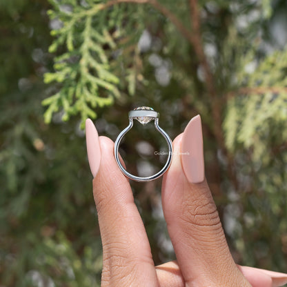 Oval bezel-set solitaire ring viewed from front, silver-toned band and prongless setting