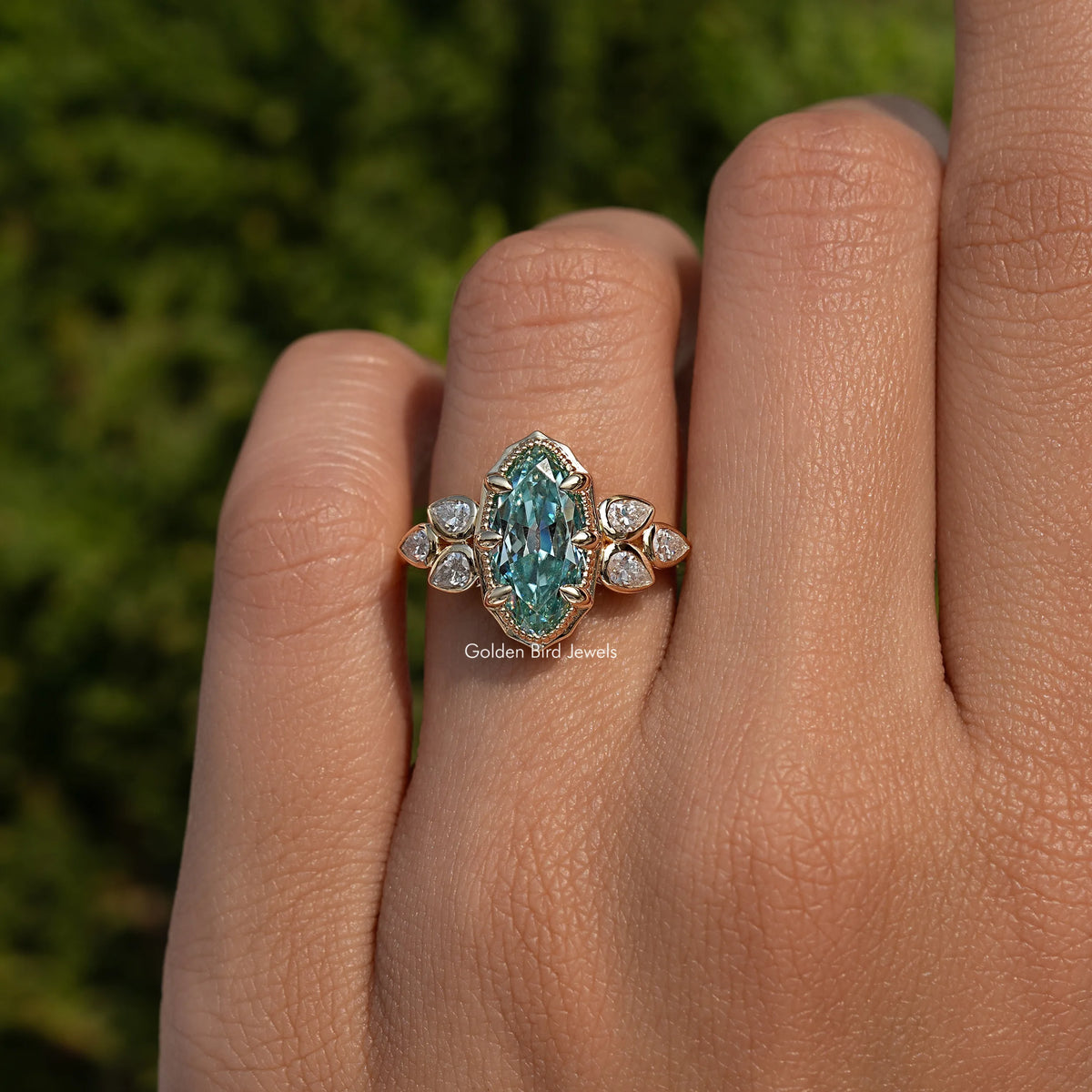 Blue oval moissanite ring with four round side stones, ornate prong setting