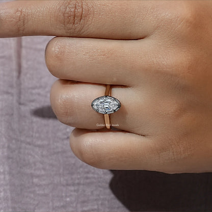 Oval moissanite bezel-set solitaire ring on gold-tone band, close-up on finger