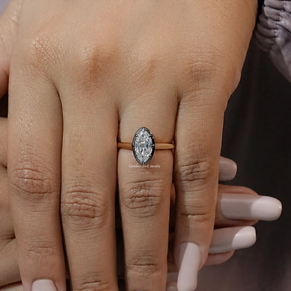 Oval moissanite solitaire ring with bezel setting on gold-tone band, worn on hand