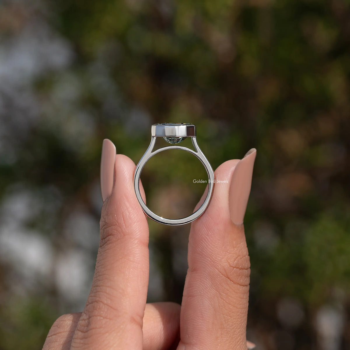 Bezel-set solitaire ring with round band and dark green step-cut stone, top view