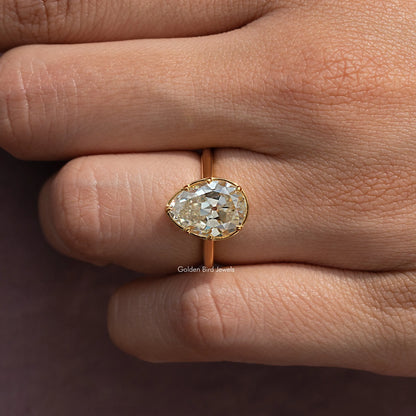 Gold-tone pear moissanite solitaire ring with large center stone, close-up