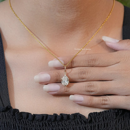 Hand holding gold-tone pear-cut moissanite solitaire pendant with teardrop stone