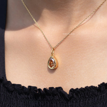 Gold teardrop pendant necklace with champagne pear-cut gemstone close to neckline