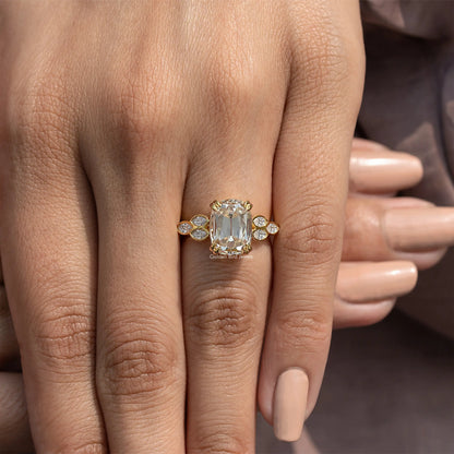 Gold-tone cushion-cut moissanite ring with four round side stones, close-up on hand