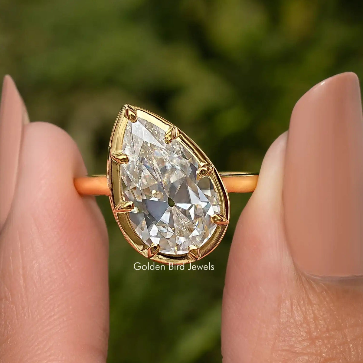 Pear-shaped solitaire engagement ring with gold-tone frame and visible facets