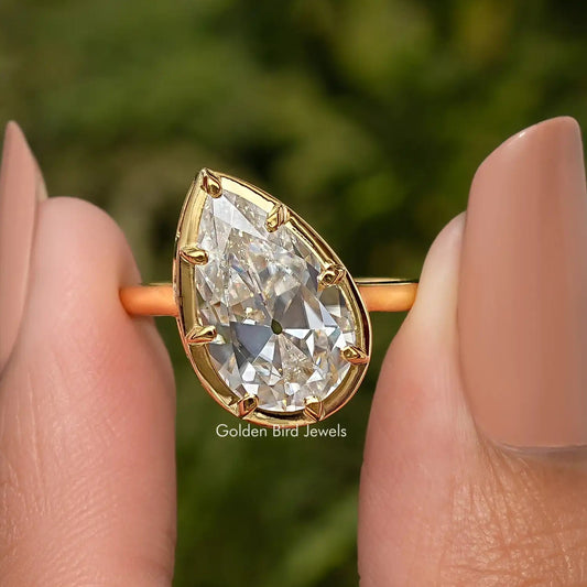 Pear-shaped solitaire engagement ring with gold-tone frame and visible facets