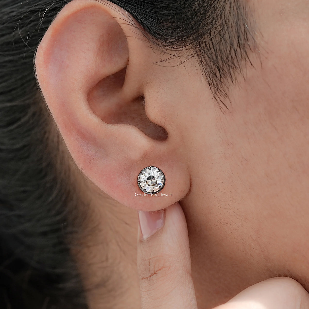 Round moissanite stud earrings on ear, close-up with butterfly back visible
