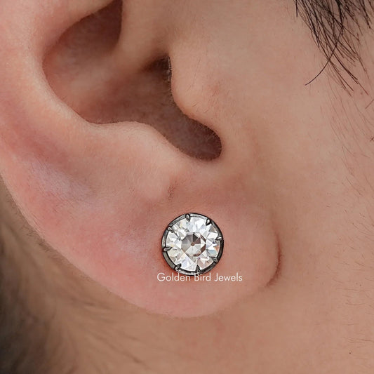 Round moissanite stud earrings close-up on ear showing bezel-set center stone