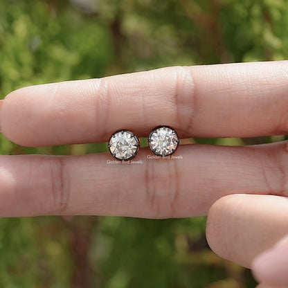 Round moissanite stud earrings in hands, two stones side by side