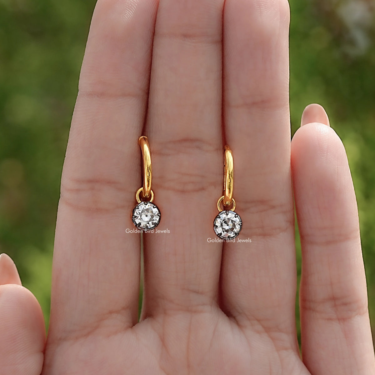 Pair of gold-tone dangle earrings with round moissanite stones