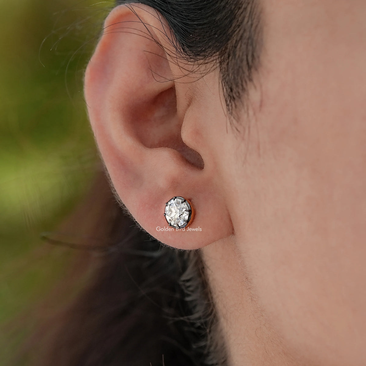 Round moissanite stud earrings on ear with circular faceted center stone