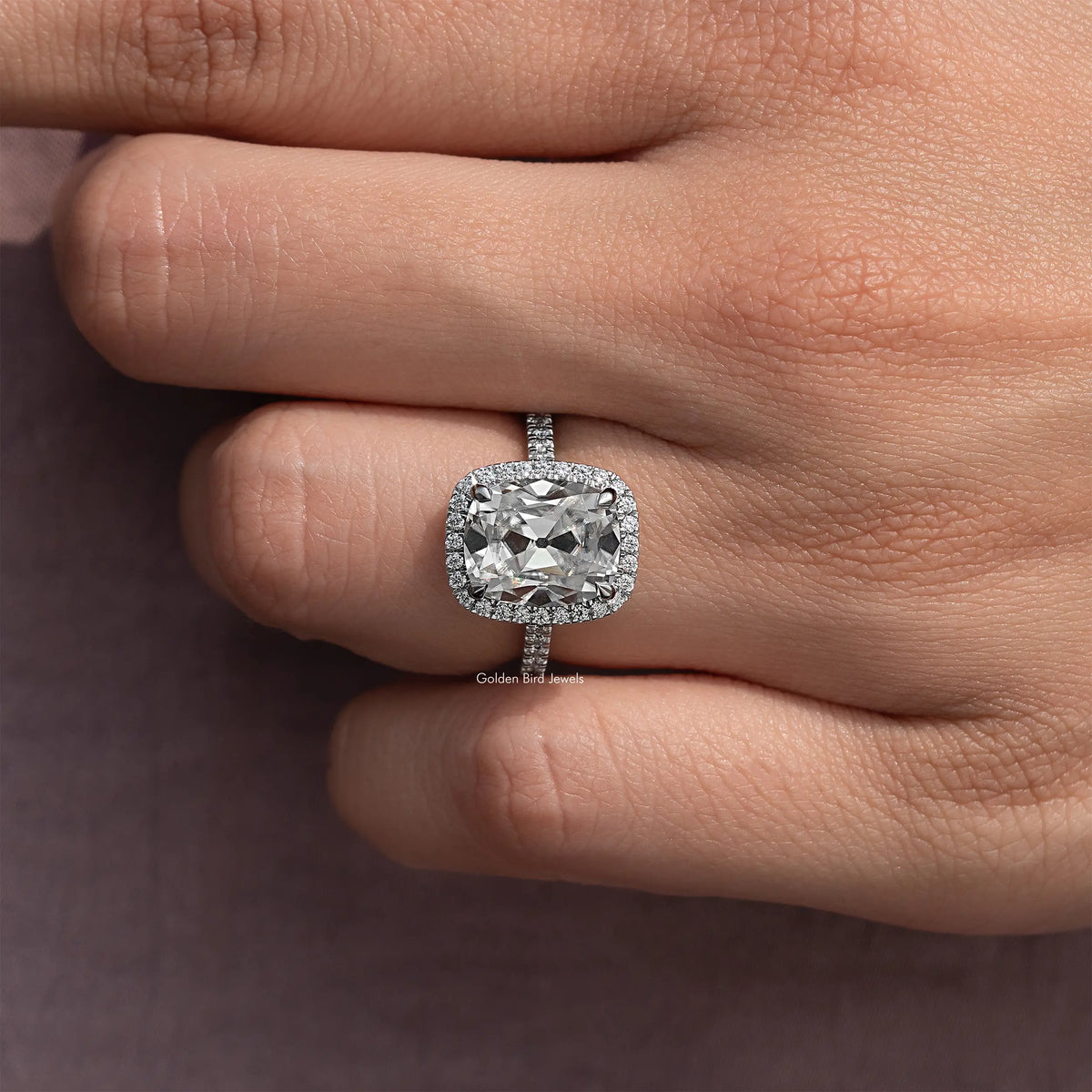 Close-up halo cushion-cut moissanite ring on hand, sterling silver band and prongs